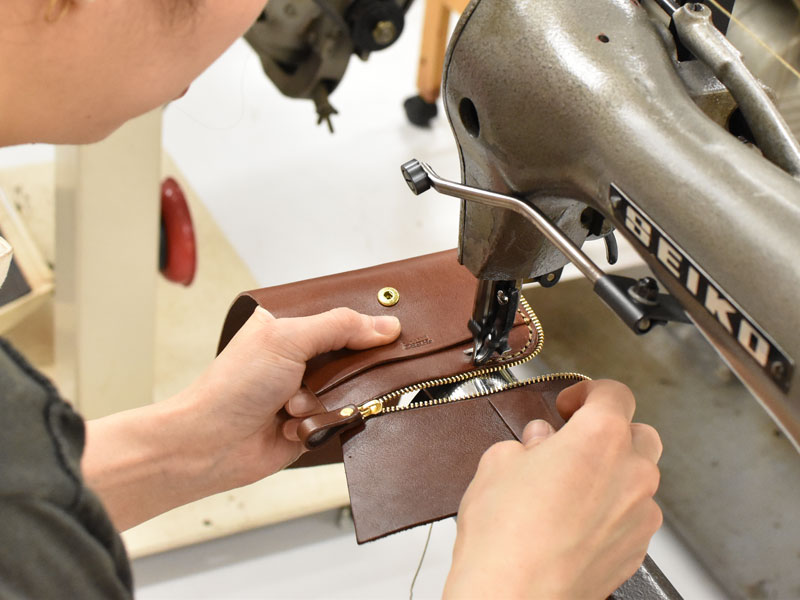 小型の二つ折り財布(WS-64)のファスナーを縫い付ける様子
